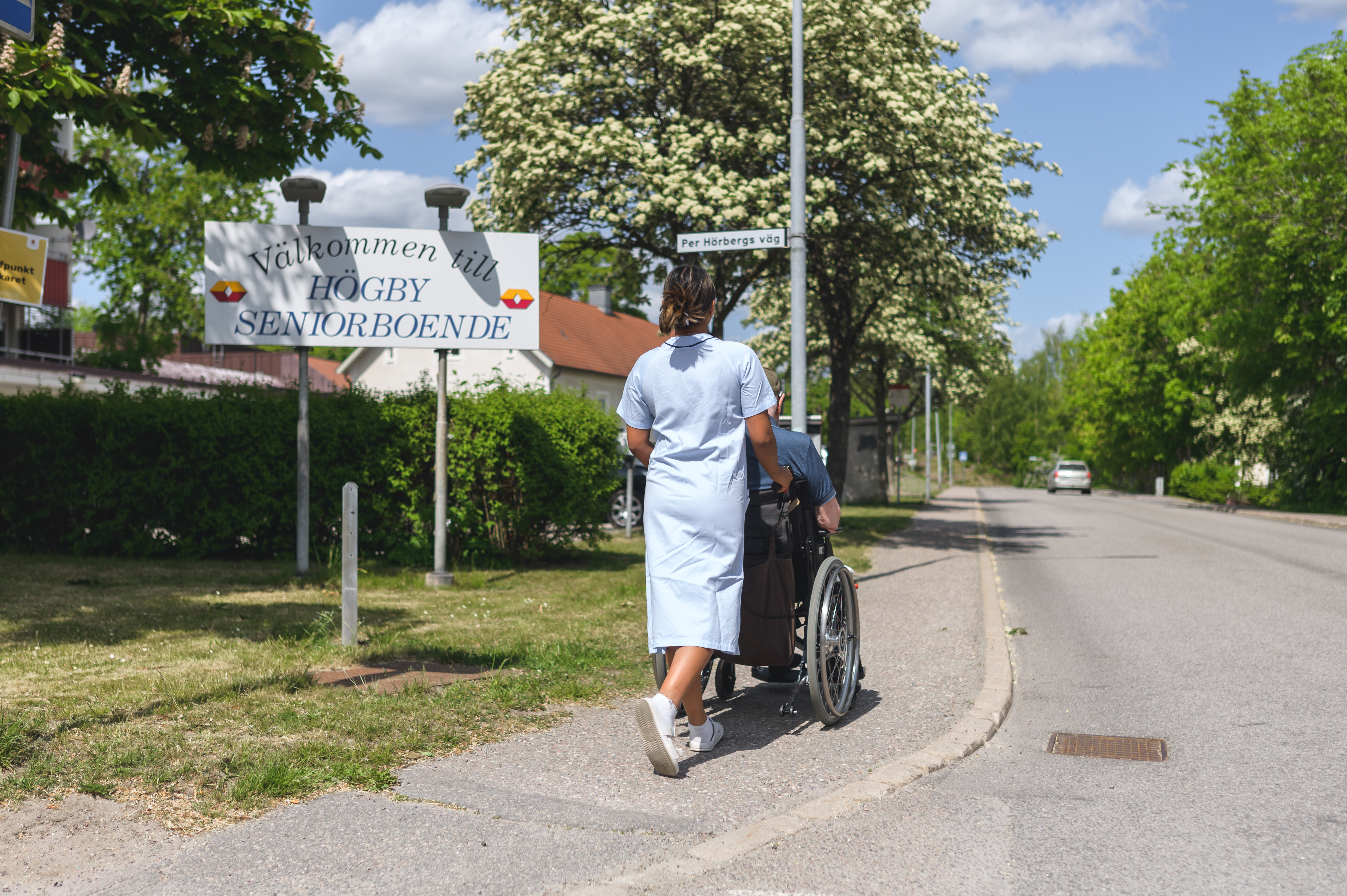 På bilden syns hemtjänstpersonal som tar en promenad med en funktionshindrar person utanför Högby Seniorboende i Finspång.